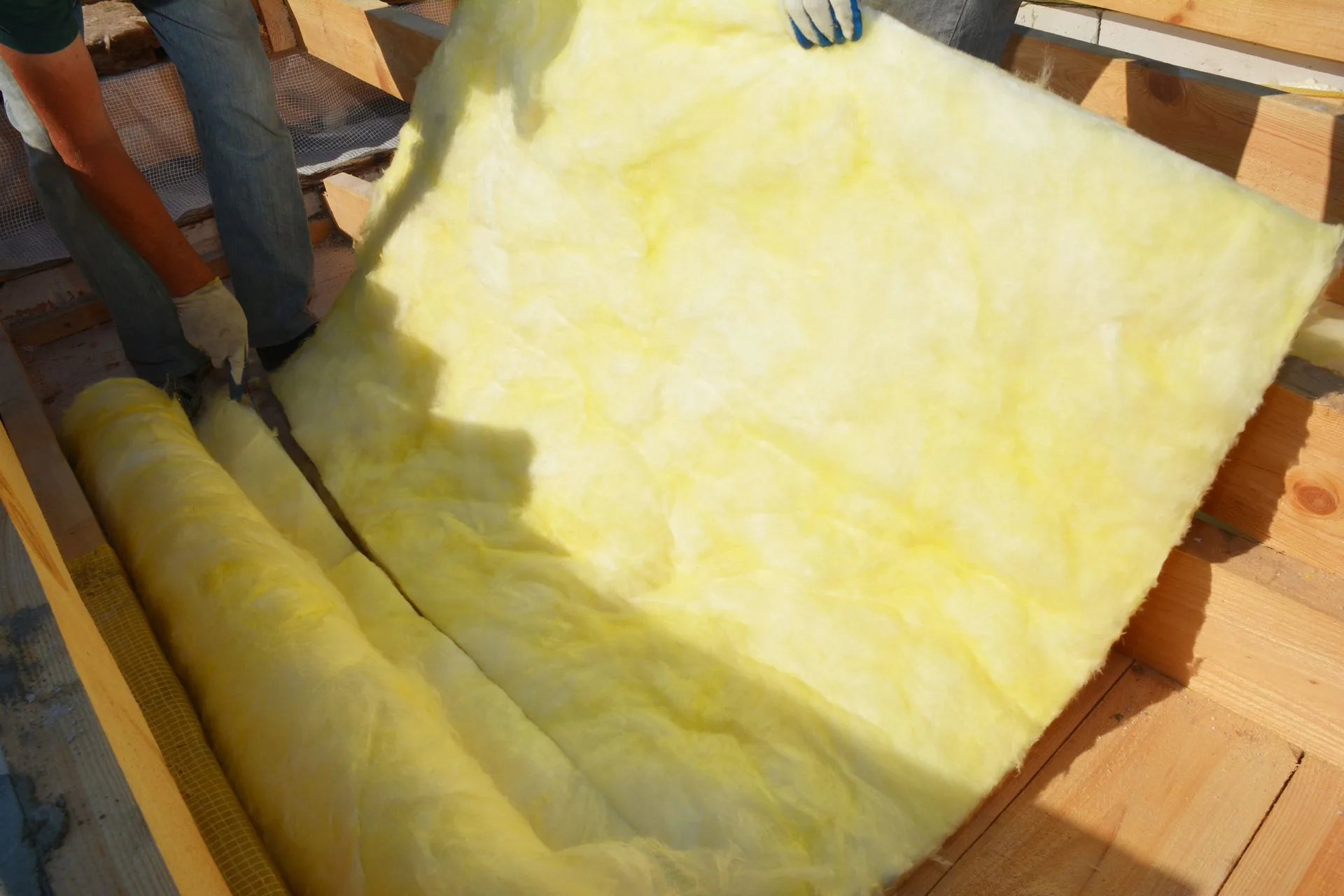 Installers rolling out fiberglass batt insulation between floor joists in a Lubbock, TX home Installers rolling out fiberglass batt insulation between floor joists in a Lubbock, TX home